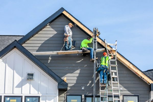Roofing contractors on ladders installing new roofing