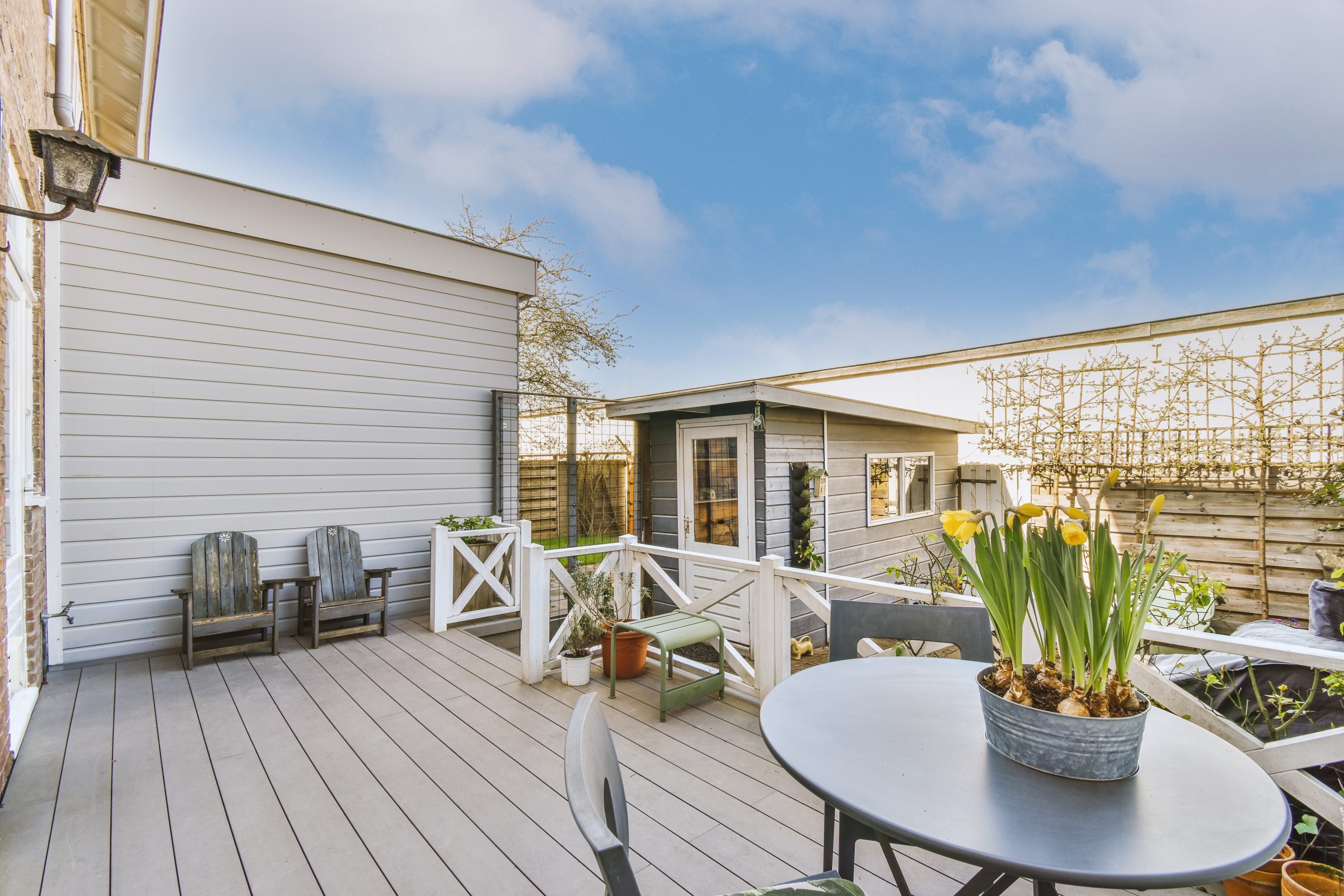Neat paved patio with sitting area and small garden near wooden fence