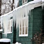 A house with large icicles hanging from the roof, illustrating the formation of ice dams and the need for prevention tips