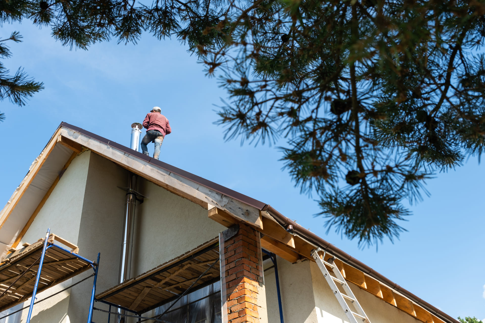 roofer-standing-on-tall-house-roof-near-chimney