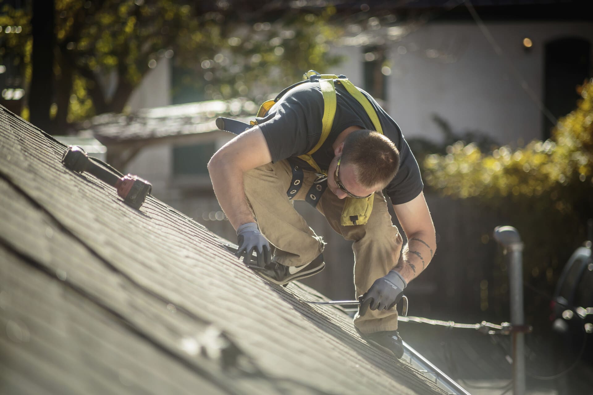 Worker in harness repairing roof shingles