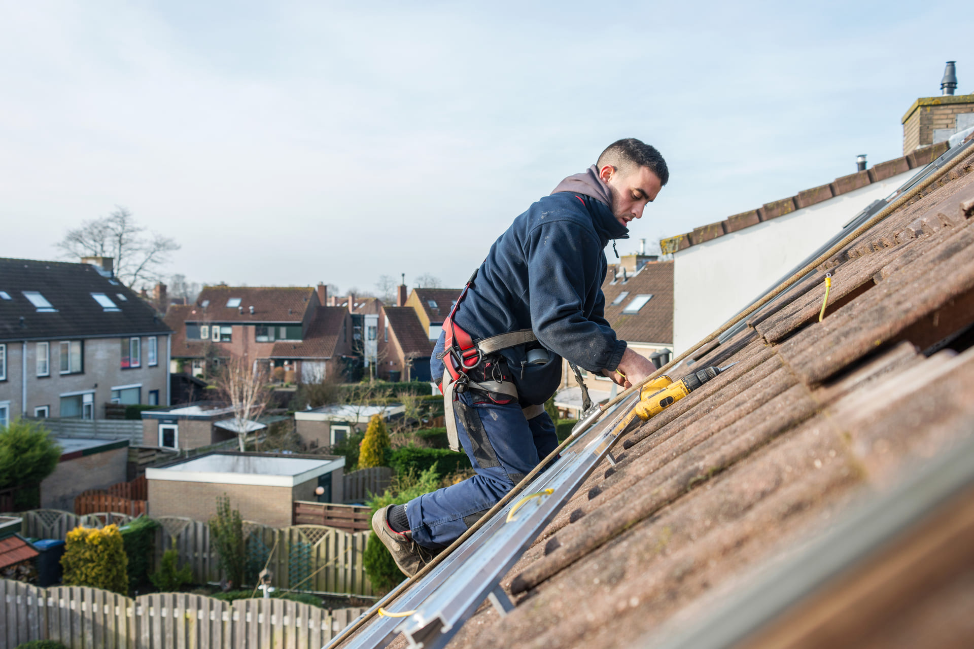 worker-installing-solar-panels-on-a-tiled-roof-with-drill