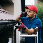 worker-making-a-phone-call-while-replacing-gutters