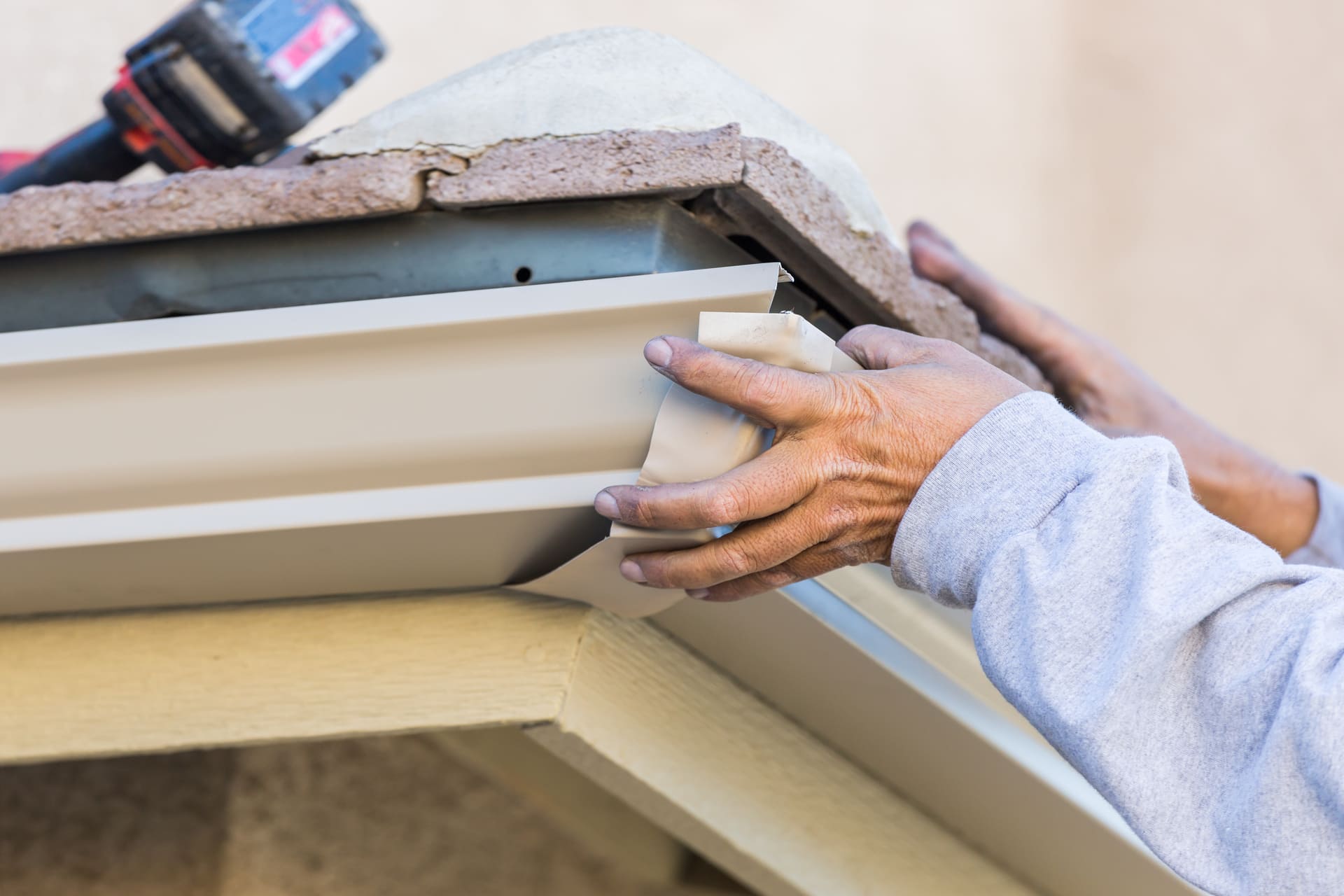 worker attaching aluminum rain gutter