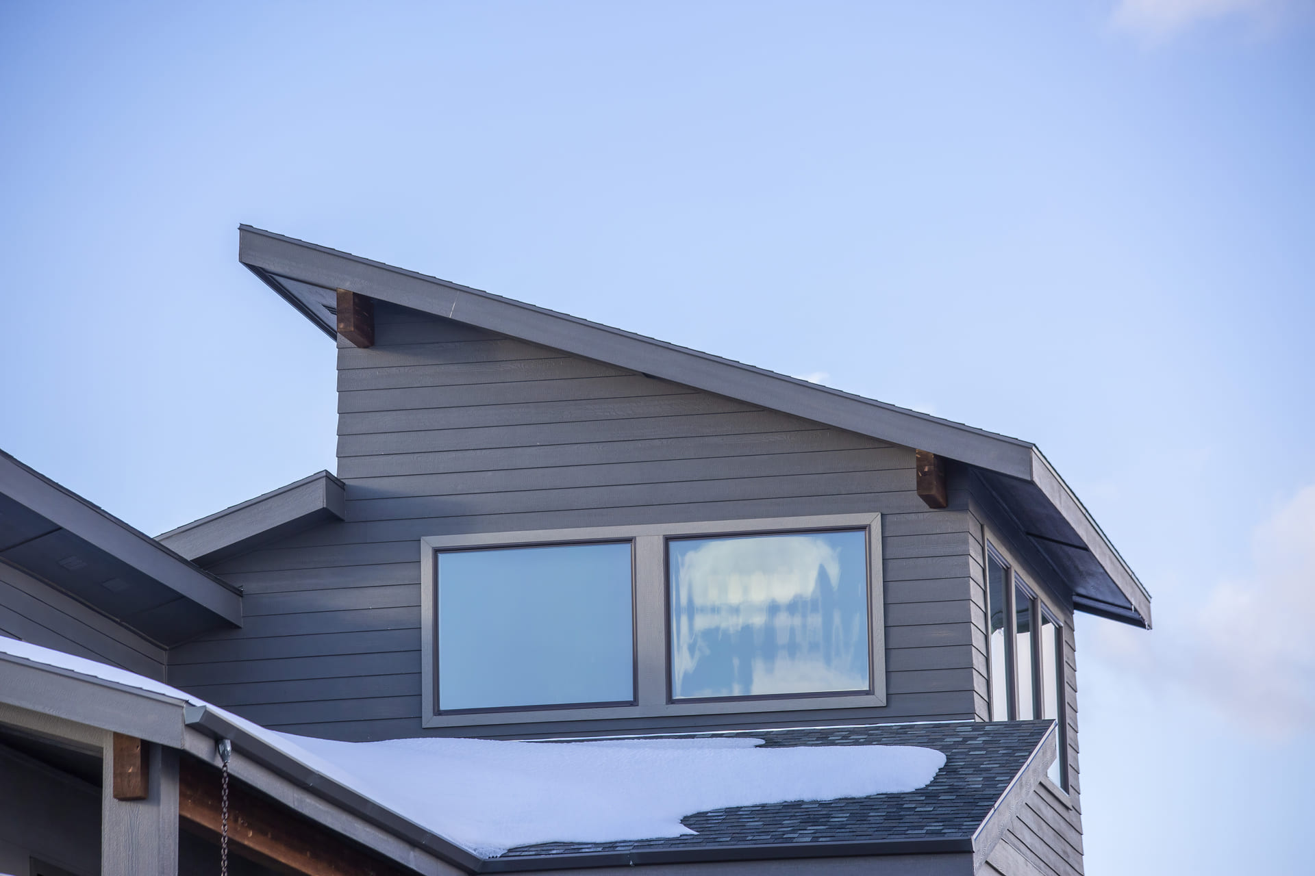 modern-home-with-gray-horizontal-siding-and-snow-on-the-roof