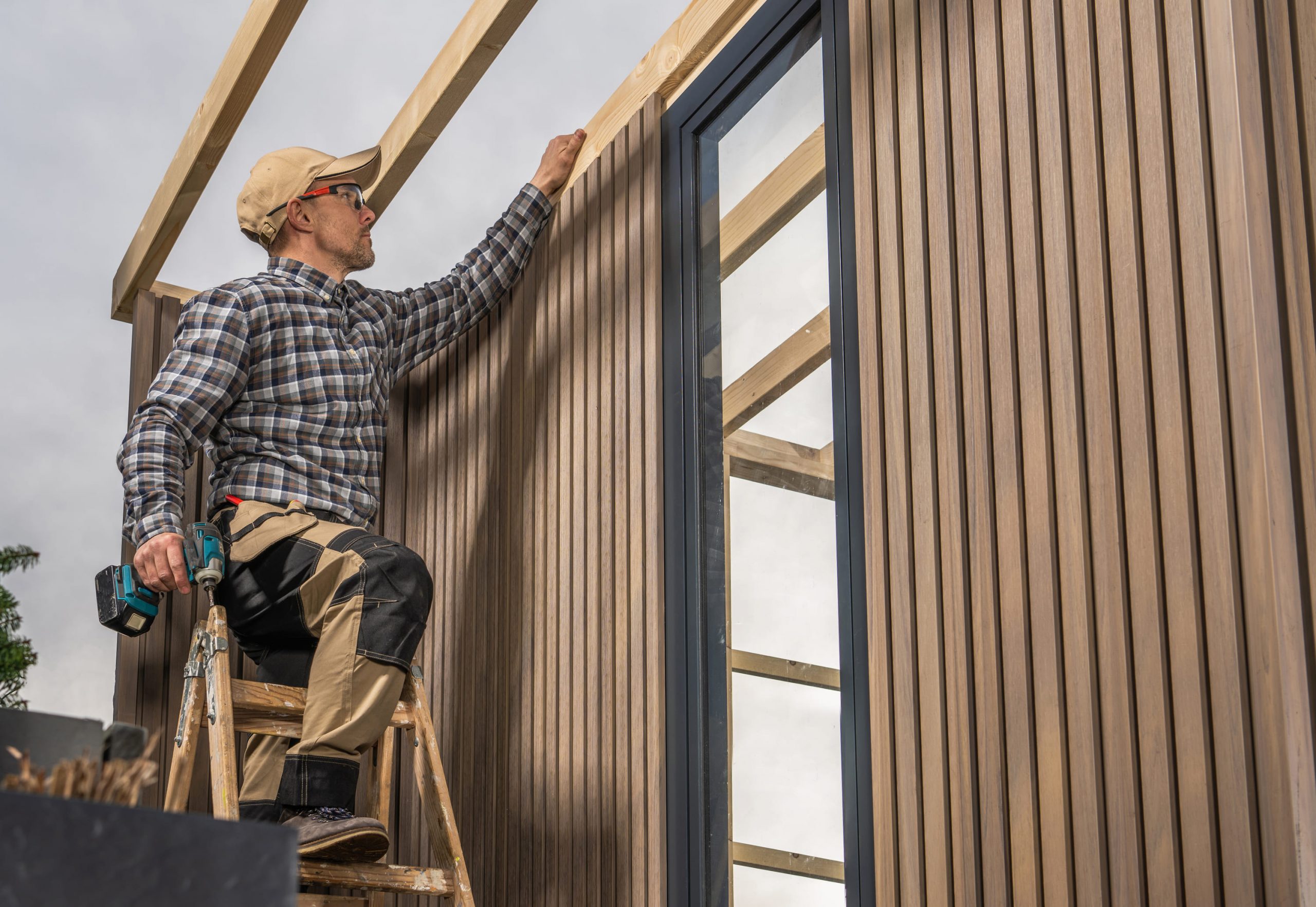 carpenter-installing-vertical-wood-siding-on-modern-building-frame