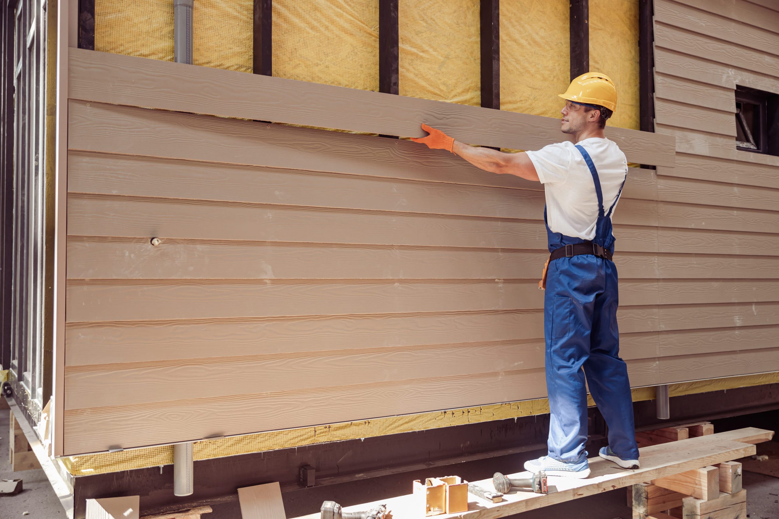 construction-worker-attaching-horizontal-siding-panels-to-house-exterior