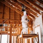 worker-in-protective-suit-applying-spray-foam-insulation-in-attic-during-home-renovation