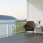modern-home-balcony-with-two-brown-chairs-and-a-small-table-overlooking-a-scenic-water-view