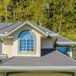 gray-shingle-roof-with-arched-dormer-window-surrounded-by-trees