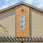 house-gable-end-with-tan-vinyl-lap-siding-cedar-shake-accent-panel-three-vertical-windows-and-pergola-below